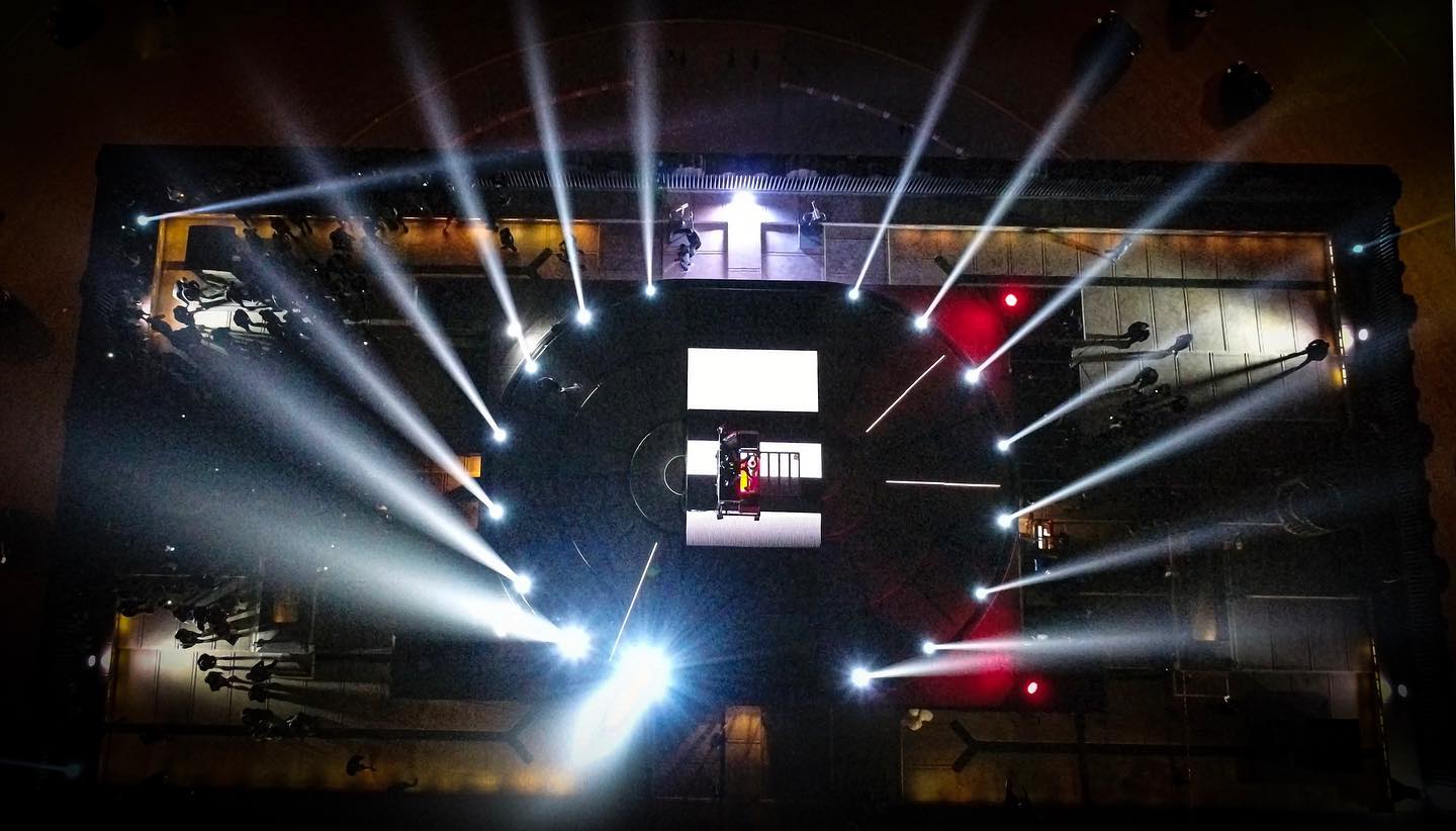 DJ Snake at his decks amid beams of light during his performance at the Arc de Triomphe