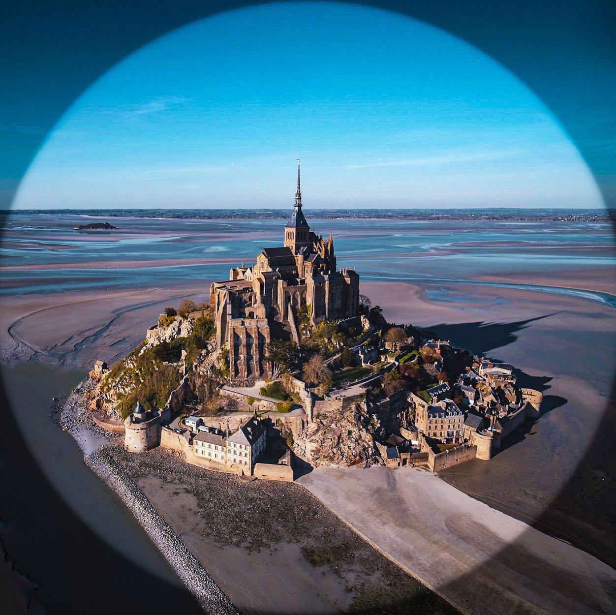 Mont-Saint-Michel and its bay, seen through an abbey arch