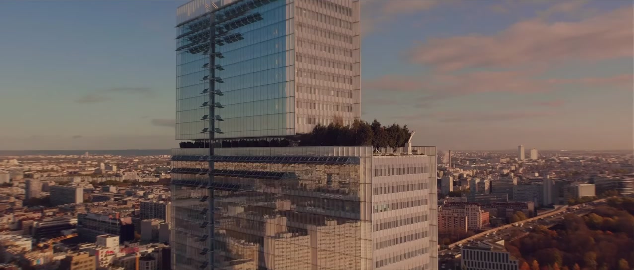 Vue aérienne large du Tribunal de Paris et des toits de la capitale sous un ciel rosé de fin de journée